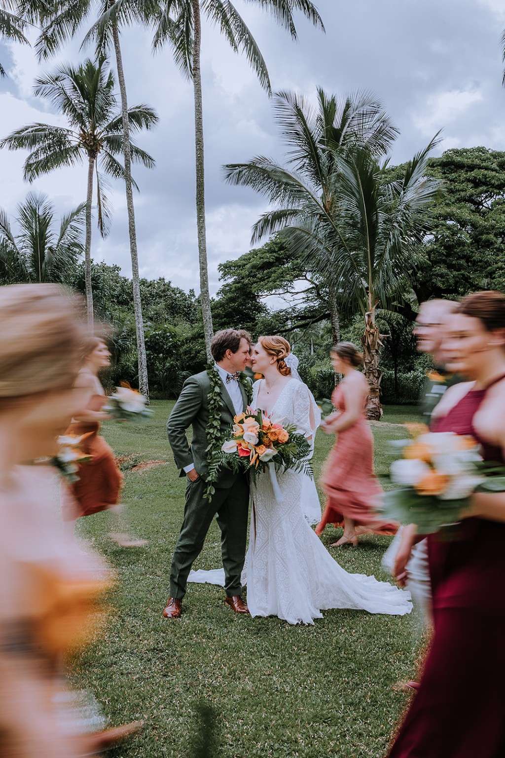 Wedding couple surrounded by their party beneath palms on Oʻahu
