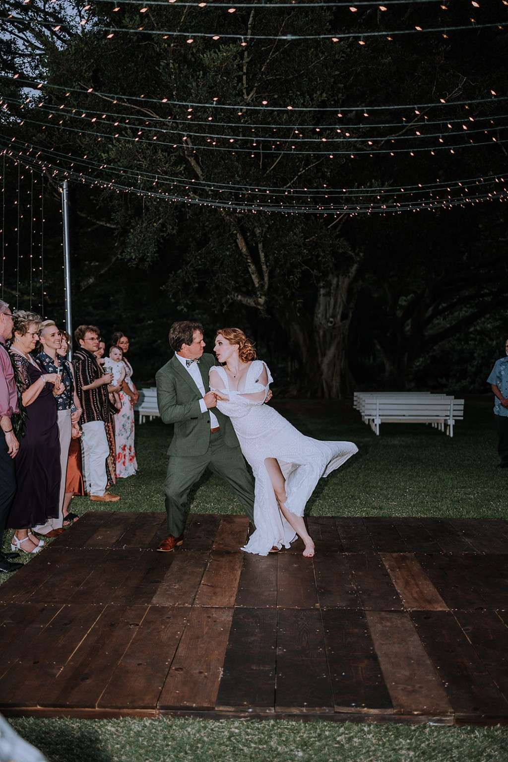 Couple dancing outdoors beneath string lights